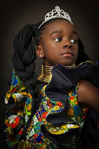 a young girl in a colorful dress with a tiara